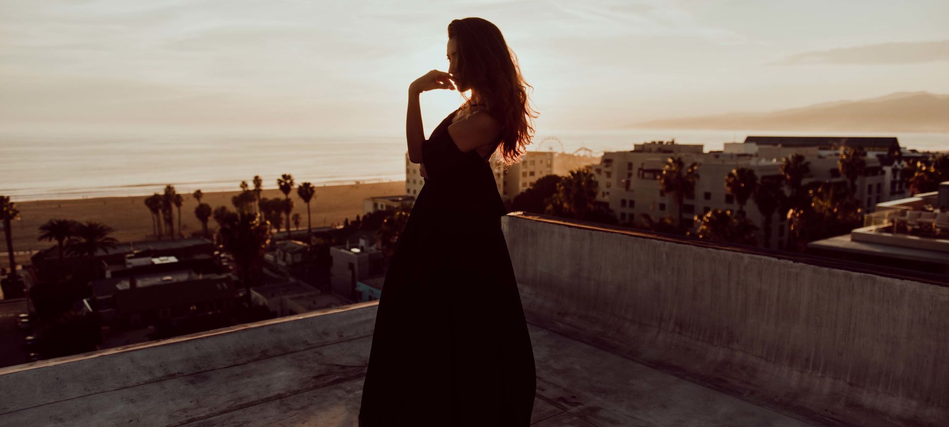 A Woman on the Roof of a Building Looking at the Sunset