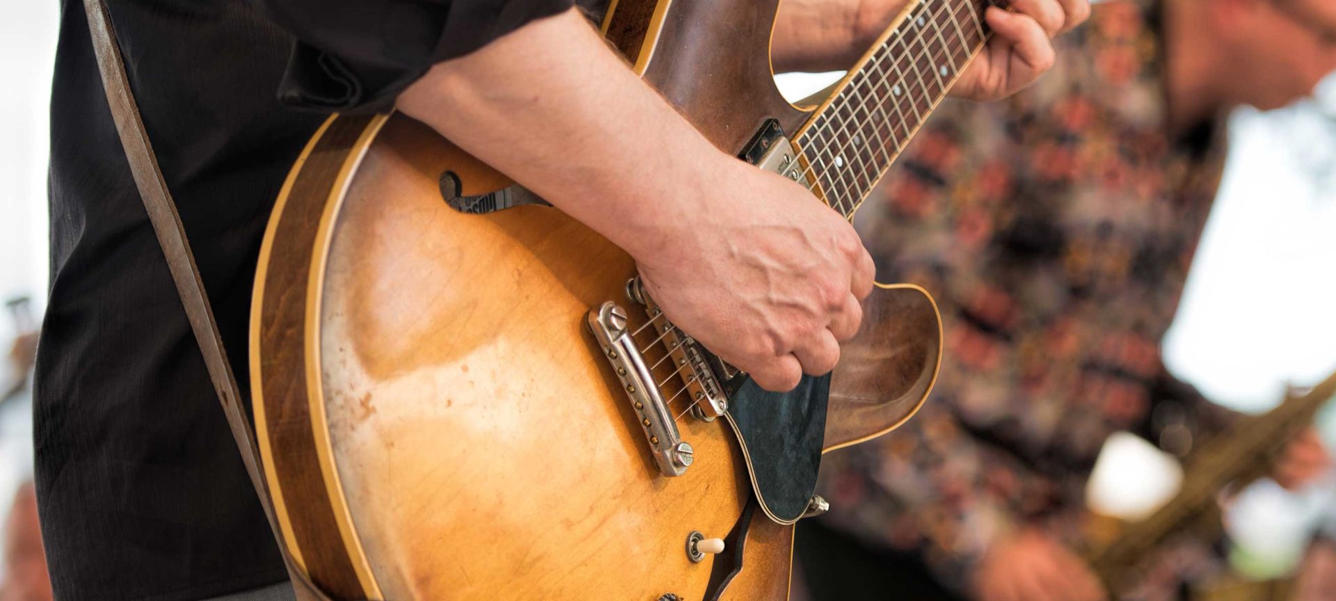 A Close Up Of A Person Holding A Guitar
