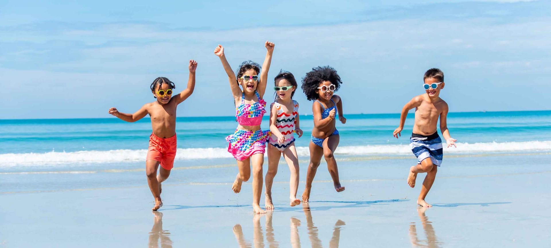 A Group Of Kids Jumping On A Beach