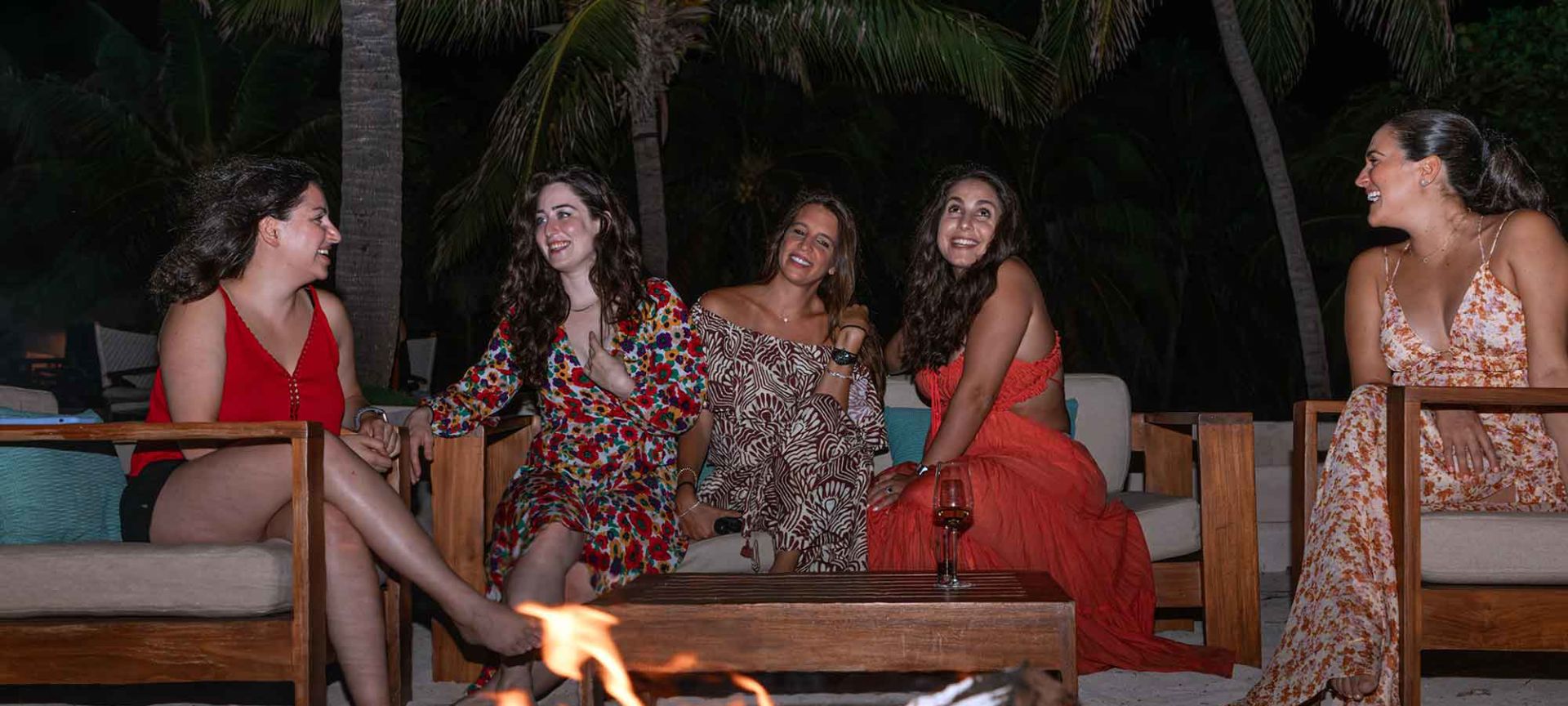 A Group Of Women Sitting Around A Fire
