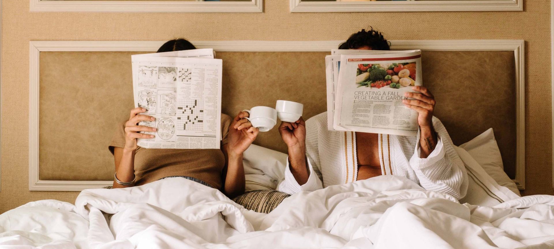 A Person Reading A Newspaper On A Bed